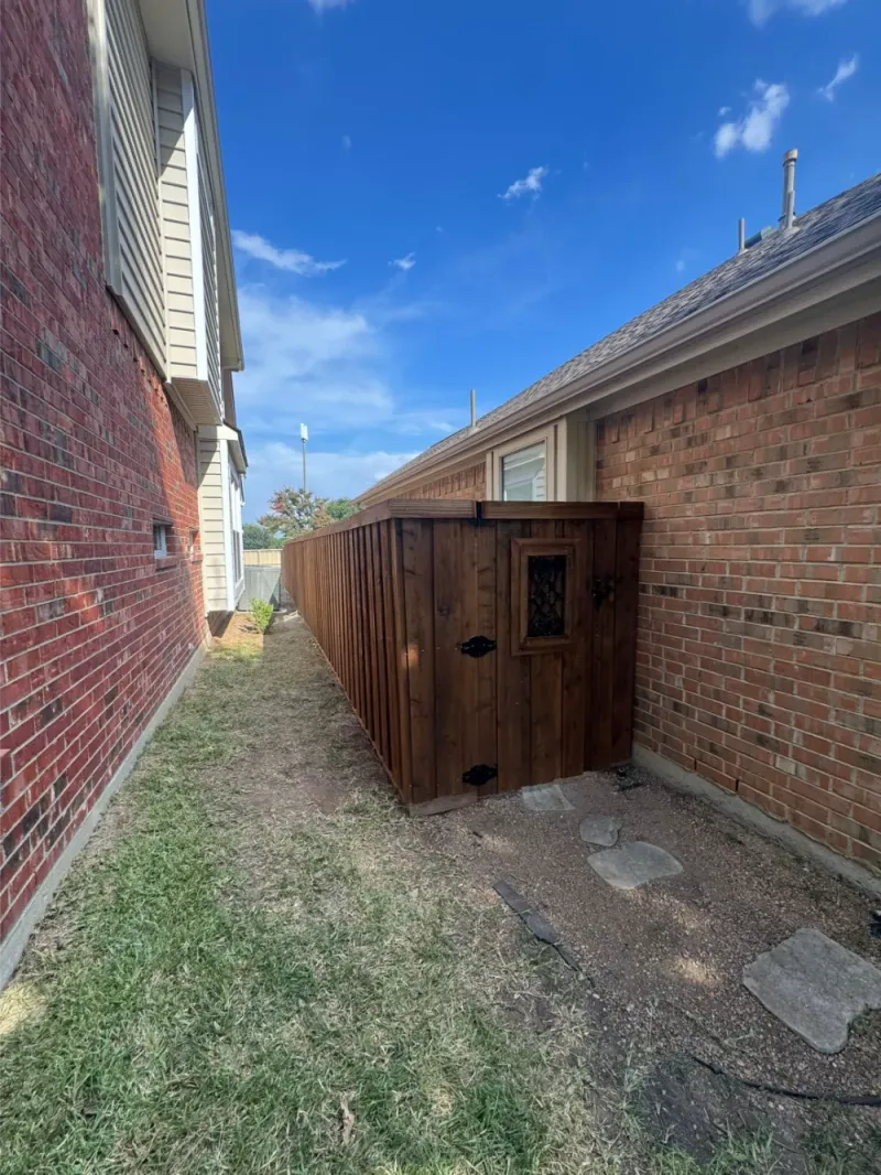 A board-on-board fence with a side gate beside the house.