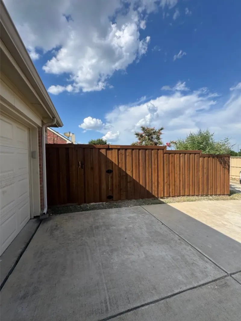 A board-on-board cedar gate beside a garage.