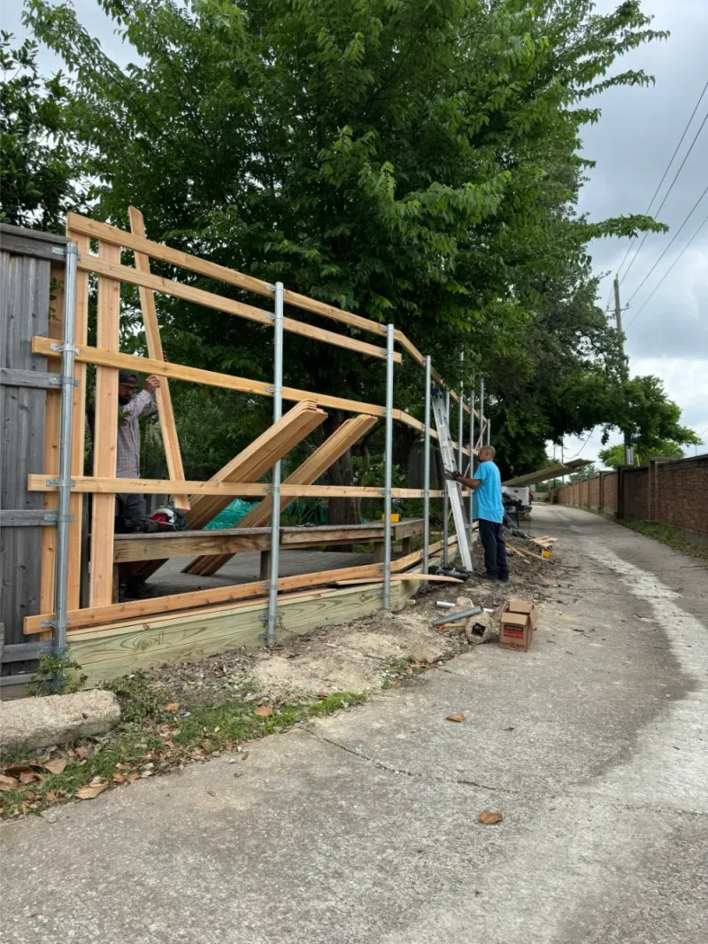 Crew framing a new fence along an alley.