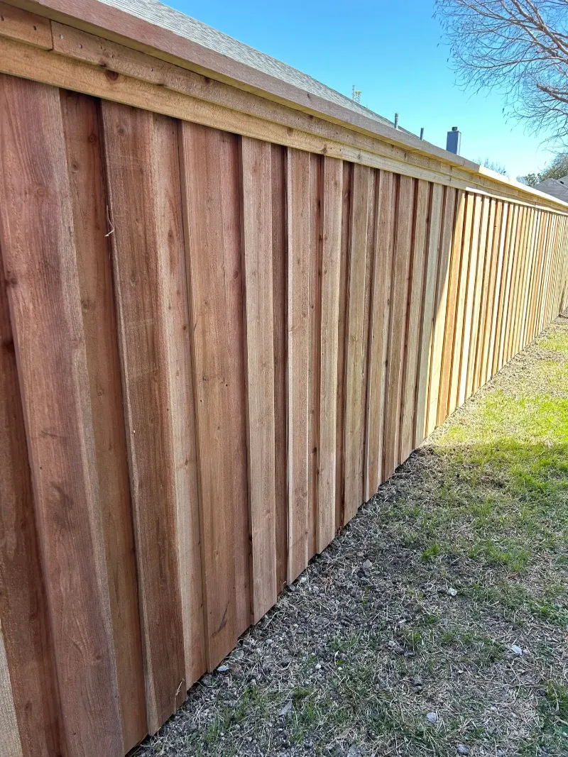 A fence showing the transition between raw wood and finished color.