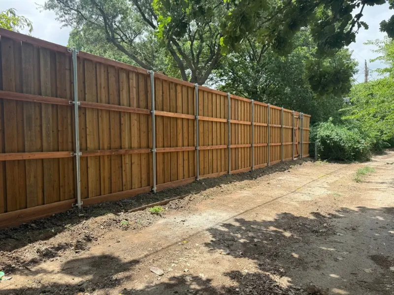 A finished fence line running the length of a shaded alley on steel posts.